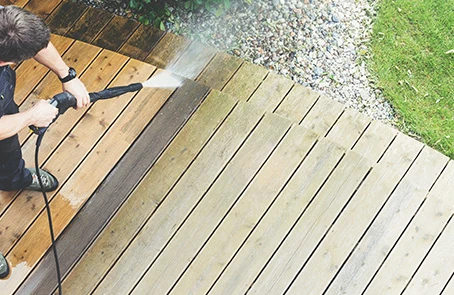 Person pressure washing wood deck.