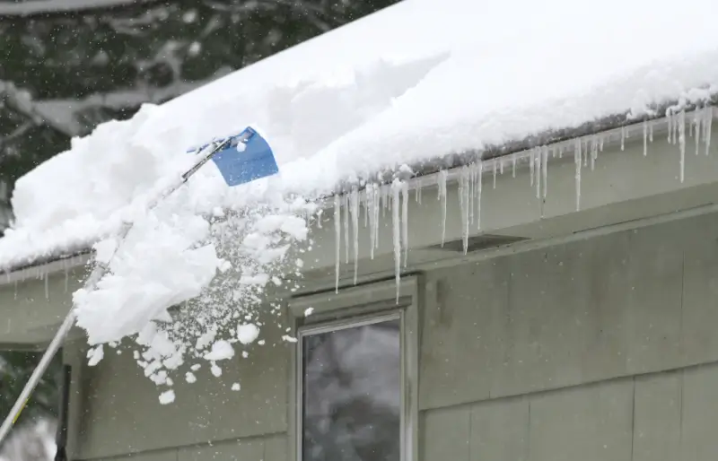Person removing snow on the roof after snow storm