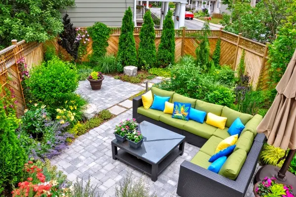 A beautiful small, urban backyard garden featuring a tumbled paver patio, flagstone steps, and a variety of trees, shrubs and perennials.
