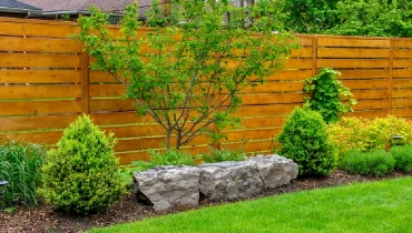 An Asian inspired and beautifully maintained garden features large rocks and minimalist style cedar fencing