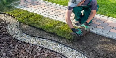 man rolling out turf next to stone path