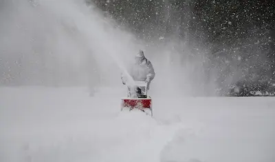 man blowing snow using a snow blower