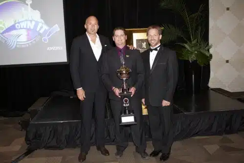 The Grounds Guys of Collingwood team holding Top Sales Award in front of stage.